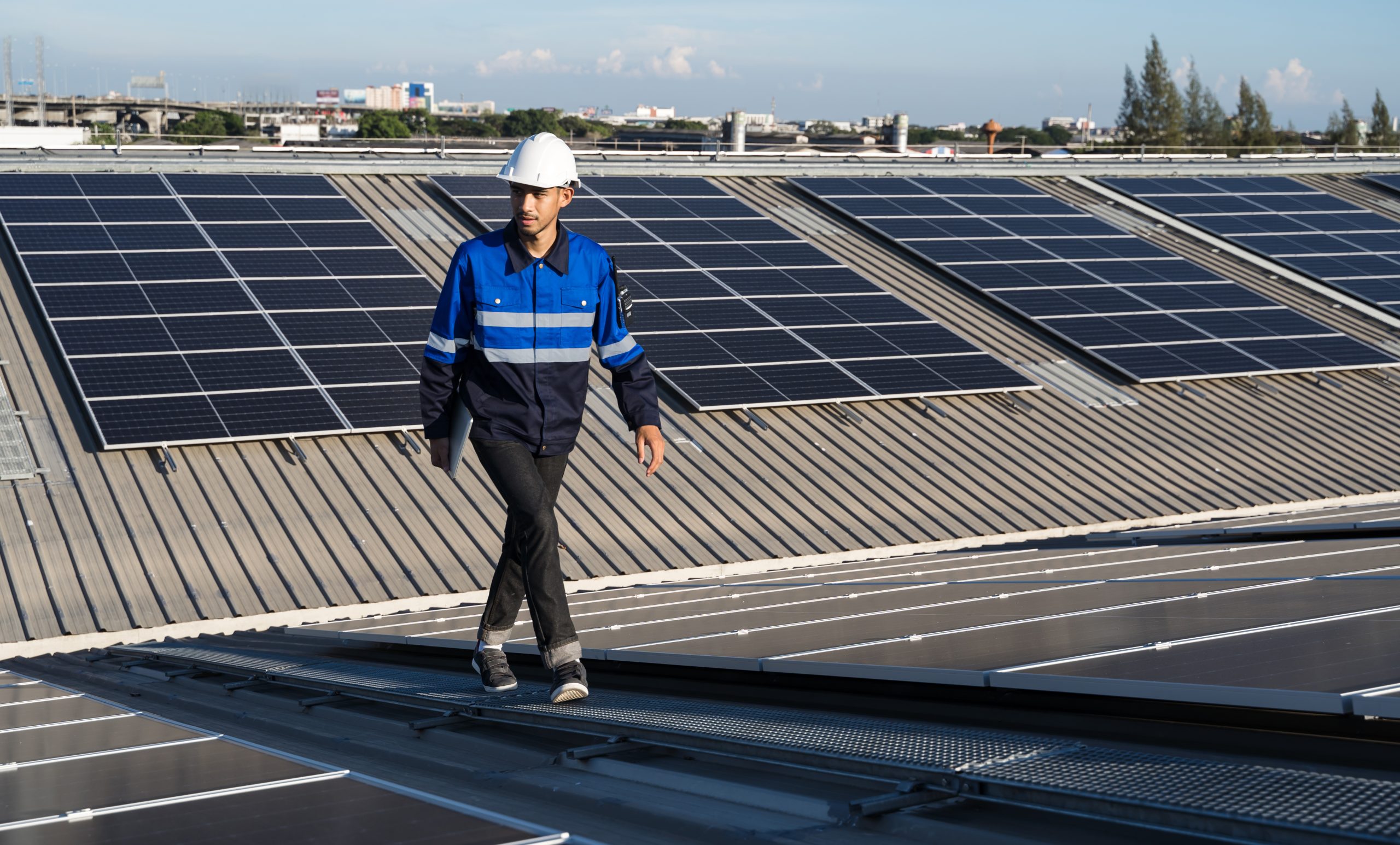 Portrait of Asian engineer on background field of photovoltaic solar panels solar cells on roof top factory.