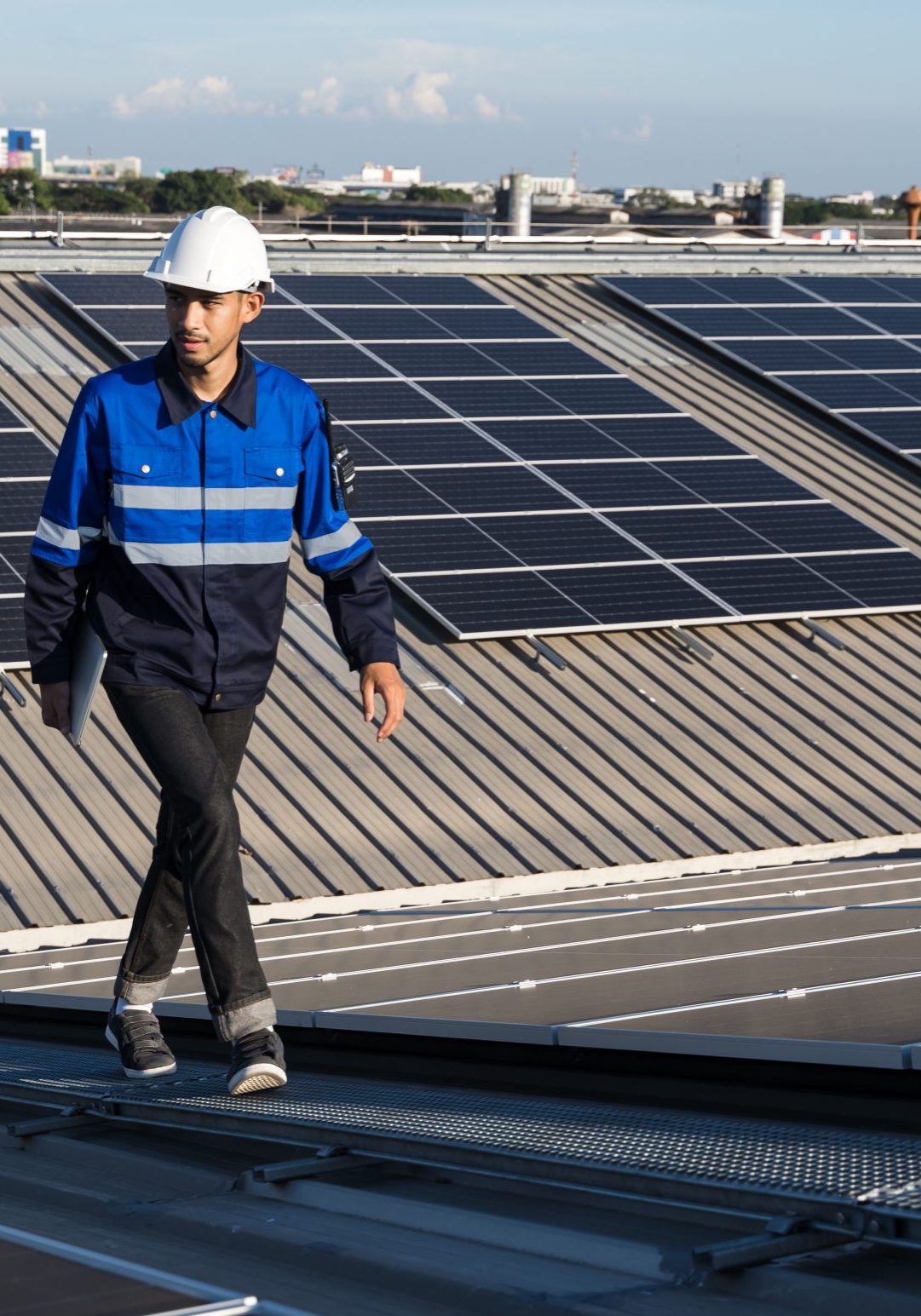 Portrait of Asian engineer on background field of photovoltaic solar panels solar cells on roof top factory.