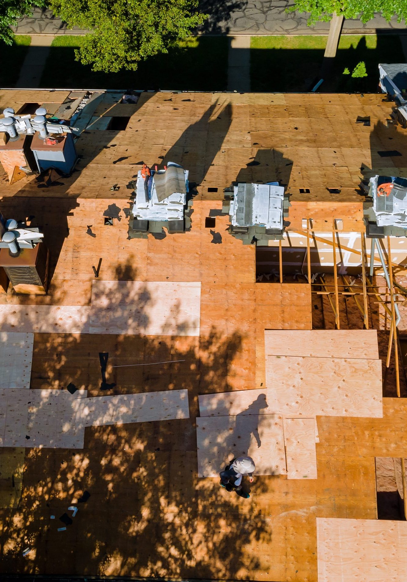 Roof repair, worker with replacing gray asphalt tile shingles on house roofing a construction worker standing on a roof covering