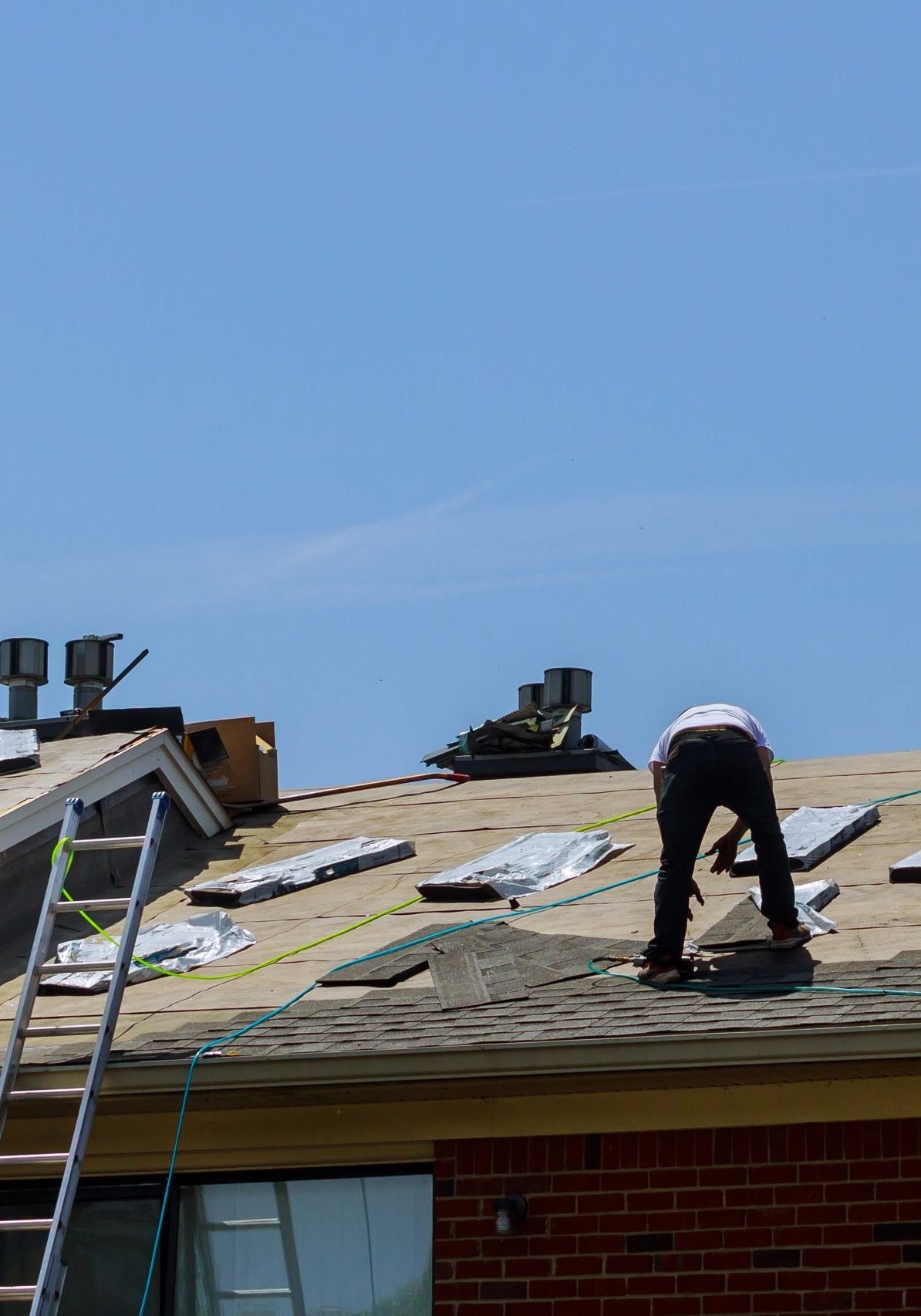 Roof repair, worker with replacing gray tiles shingles on house being applied